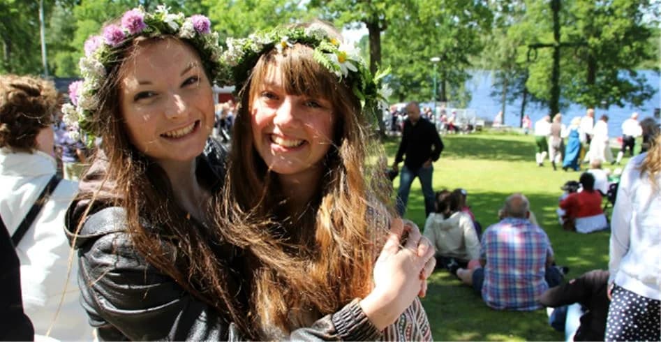 En grupp människor ler och njuter av somriga utomhusaktiviteter vid Eksjö Camping & Konferens, omgiven av grönskande natur.