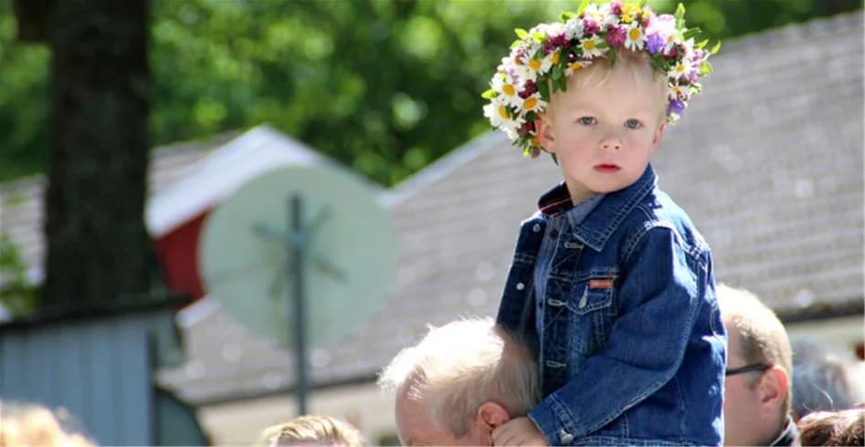 Ett glatt litet barn med blont hår håller en blomsterbukett i händerna, omgiven av en vårig atmosfär, på Eksjö Camping & Konferens.