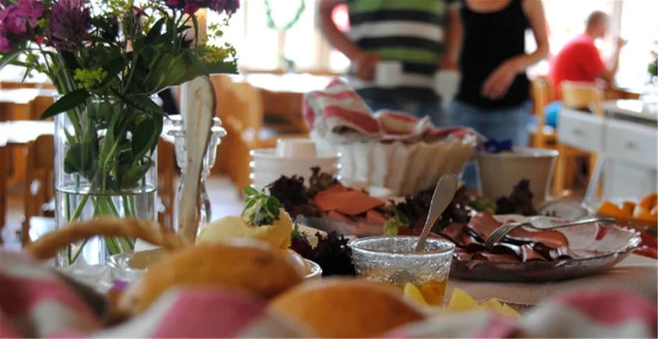 En uppdukad utomhusmåltid vid Eksjö Camping & Konferens, med tallrikar fyllda med frukt och andra ingredienser, omgiven av bord och stolar.