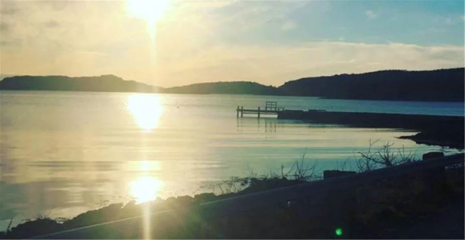 En vidsträckt vy över havet vid Fjällbacka camping, med en klar horisont i bakgrunden och vackra skiftningar i skymningsljus på himlen.