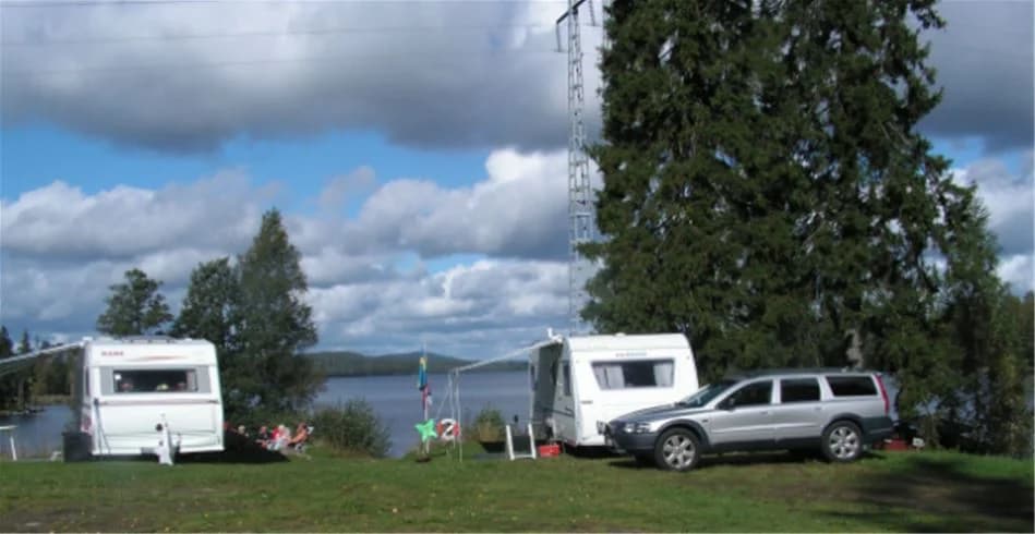 En husbil står parkerad vid en sjö på Munkebergs camping, omgiven av grönska och en rofylld miljö.