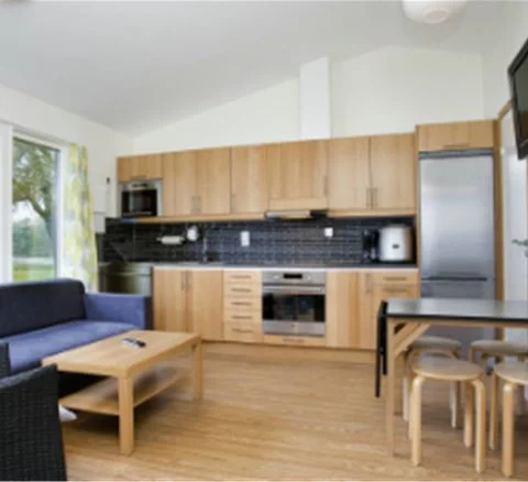 En interiörbild av Gustavsvik Resort som visar ett rum med trämöbler och lantlig inredning. Golvet är av trä och det finns stolar runt ett bord, vilket skapar en varm och inbjudande atmosfär.