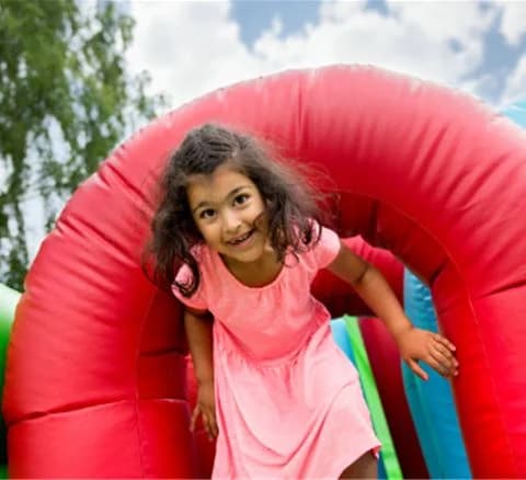 En grupp glada barn leker med rosa uppblåsbara föremål vid Gustavsviks resort, en populär semester- och rekreationsplats.