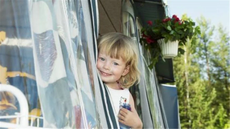 En barnfamilj leker utomhus vid Skellefteå Camping, omgiven av husvagnar och campingutrustning.