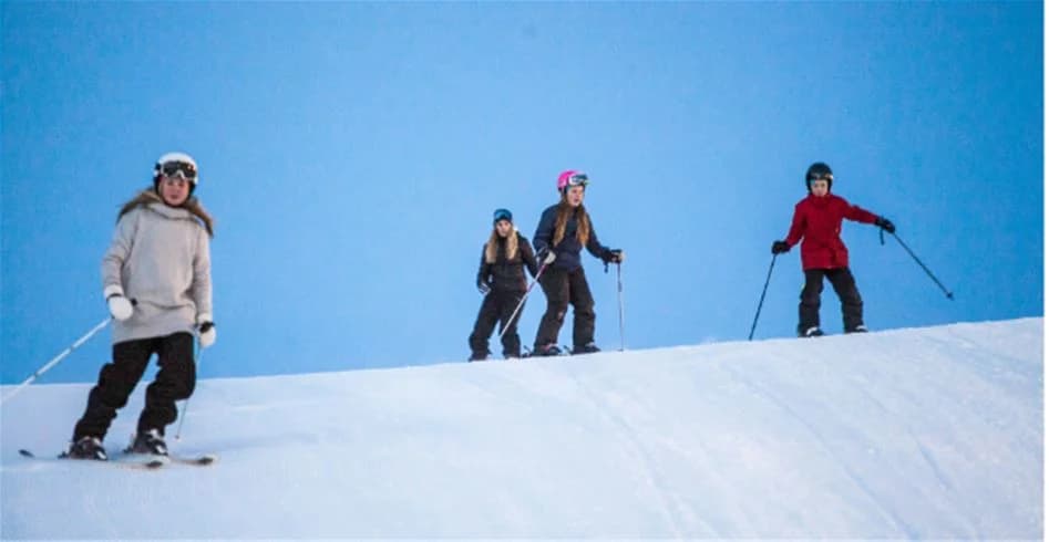 En person klädd i vinterkläder åker skidor på snötäckt mark vid Skellefteå camping, omgiven av vinterlandskap.