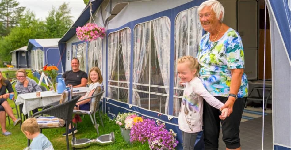 Bild av Skellefteå Camping: En solig dag med stolar under skuggande träd vid en campingplats. Perfekt för rekreation och avkoppling, lämplig för semesterfirare eller familjesammankomster.