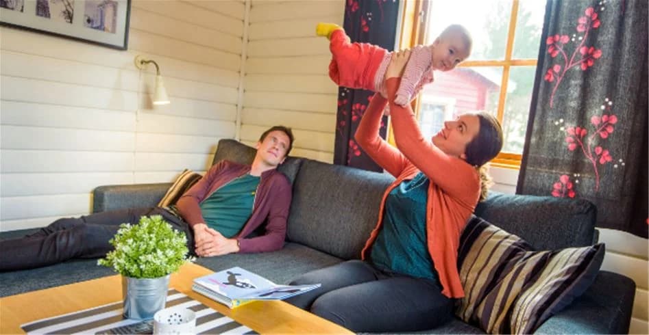 En grupp människor ler och ser glada ut medan de sitter bekvämt i en soffa inne på Skellefteå Camping.