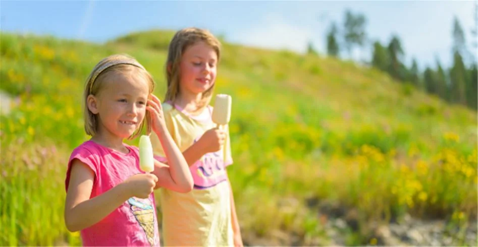 En glad och blond barn leker på en somrig äng vid Skellefteå camping, omgiven av grönskande natur och solsken.