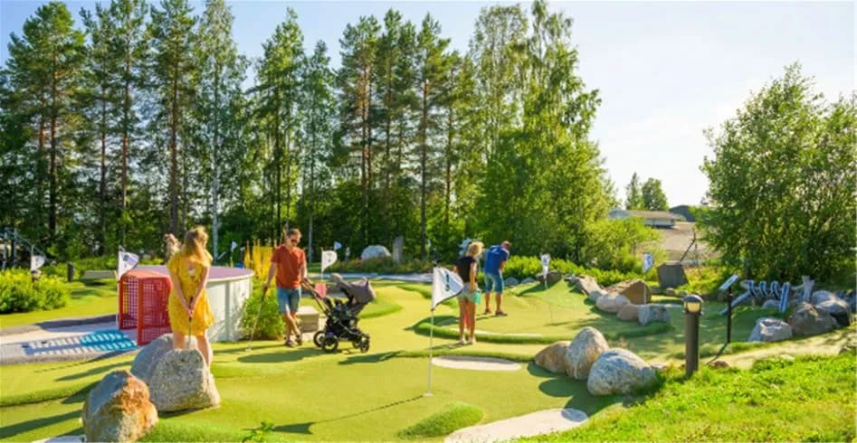 Bild av Skellefteå Camping som visar ett grönt rekreationsområde med välskött gräsmatta, trädgård och minigolfbana, vilket ger en plats för avkoppling och lek.