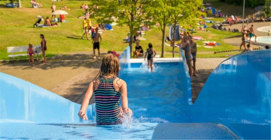 En grupp människor i badkläder leker och kopplar av i ett vattenland på Skellefteå camping under sommaren.
