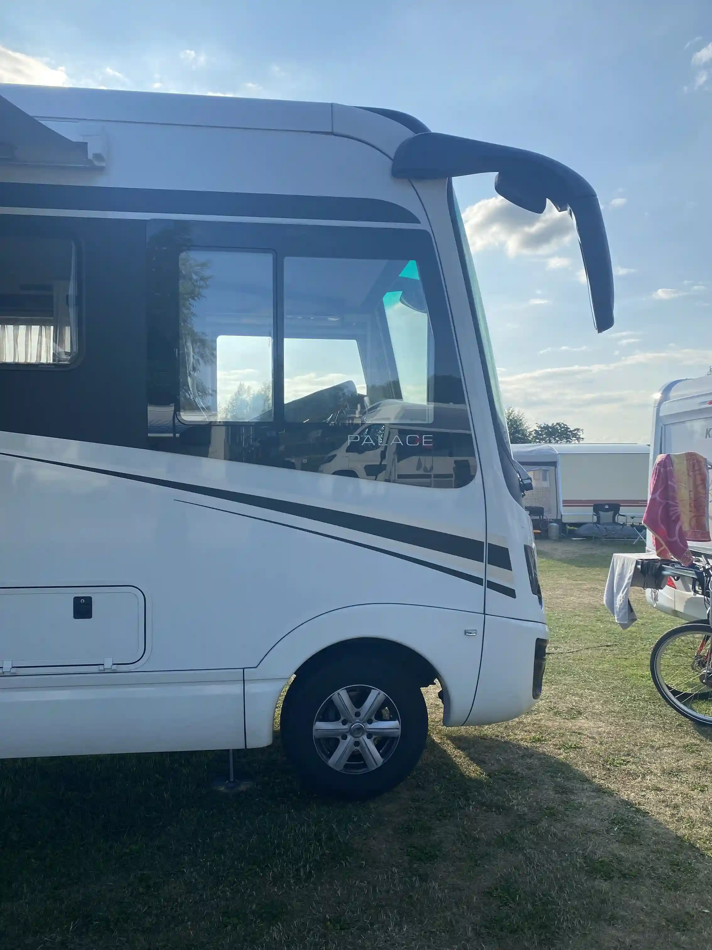 En campingplats med flera husbilar och husvagnar uppställda nära varandra, omgiven av grönska.