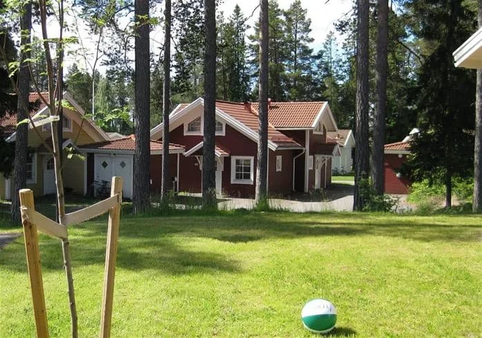 Bild av en pittoresk stuga vid Östersunds camping, omgiven av en grönskande gräsmatta och trädgård.