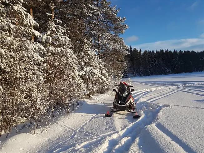 En snötäckt vinterlandskap vid Åsarna skicenter, med en snöskoter synlig i förgrunden. Perfekt för vinteräventyr, rekreation och sport.