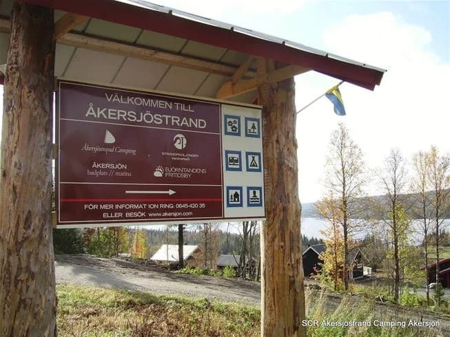En grusad stig leder genom skogsområdet vid Åkersjöstrand Camping, omgivet av grönska och tallträd.