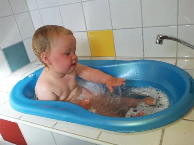 En liten barn leker i en badkar med några badleksaker på Wiggersviks camping.