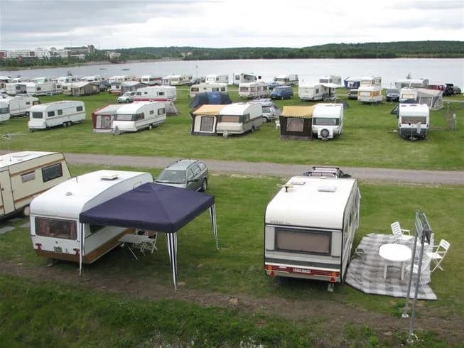 En campingplats med flera uppställda husbilar och bilar på en parkeringsplats vid Västra Kajen Camping.