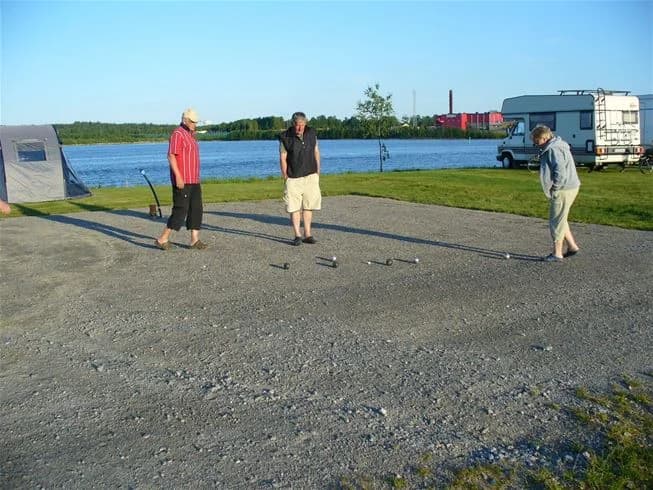 En lugn campingplats vid Västra Kajen med utsikt över kusten. Besökare njuter av fritidsaktiviteter i en naturskön miljö, perfekt för avkoppling och semester.