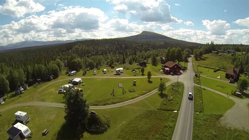 En vidsträckt landskapsscen med böljande ängar och gräsfält, som omger Vålågårdens värdshus & camping i en lantlig och naturskön miljö.