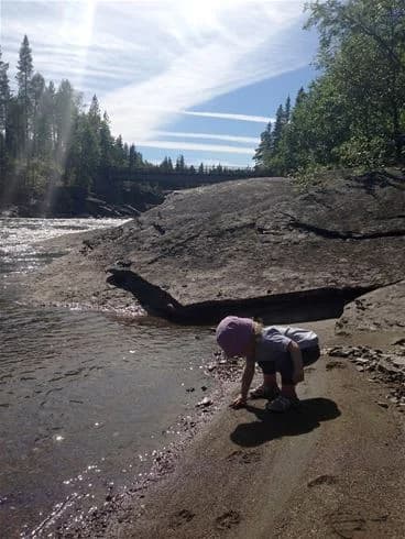 En naturskön miljö vid Vålågårdens värdshus & camping, med en strömmande å omgiven av stenar och vildmark, perfekt för avkoppling och rekreation.