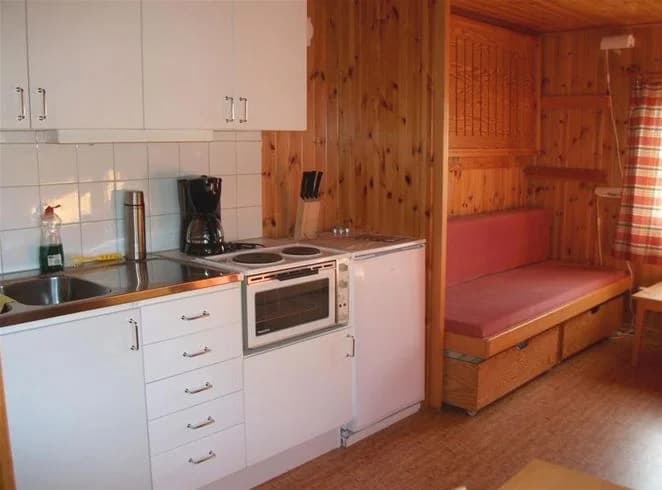 Bild av en inomhusmiljö på Vadstena camping med träinredning. Det ljusa trägolvet matchar med möbler och skåp av trä, vilket ger ett enhetligt och varmt intryck i rummet.