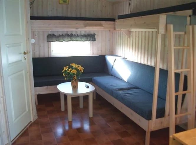 En mysig stuga med träinredning och en säng, perfekt för en campingvistelse på Vadstena Camping.