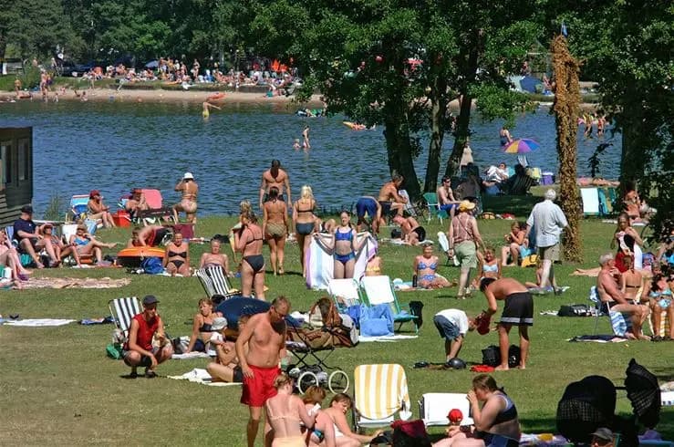 En solig dag vid Vadstena camping med semesterfirare som solar och njuter vid sjön.