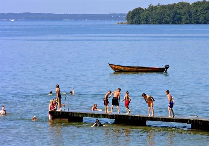 En somrig och livlig campingplats vid kusten med lekande människor nära sjön, perfekt för avkoppling och semester.