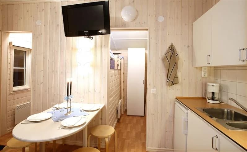 Inredning av en campingstuga med träinredning, trägolv och trätak. Rummet är enkelt möblerat och ger en rustik och hemtrevlig känsla.