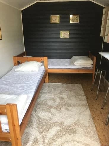 Ett rum med träinredning på Strandstuvikens havsbad & camping, inklusive en säng med vit bäddning och ett träbelagt golv.