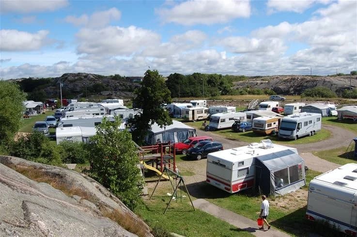 En husbil och en lastbil parkerade på Sotenäs Camping, omgivna av träd och campingfaciliteter.