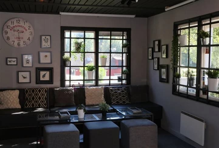 Alt-text: Interiörbild av ett mysigt vardagsrum i Rösjöbaden Camping & Stugby med en bekväm soffa, stilren inredning och rikligt med naturligt ljus.