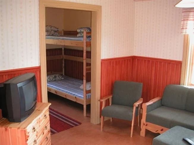 Interiör av en stuga på Näsåkers Camping & Stugby, med träinredning och bekväma möbler på ett trägolv.