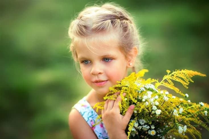 En glad flicka leker bland gula blommor en solig sommardag på Norrtälje camping.