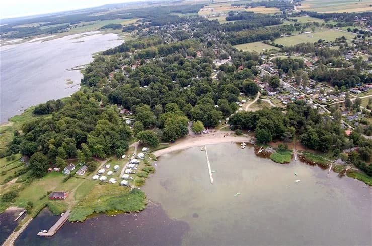 En naturskön vy över Norje Boke Camping med en strandlinje intill en sjö eller kust, där besökare kan njuta av vattnets närhet och den omgivande naturen.