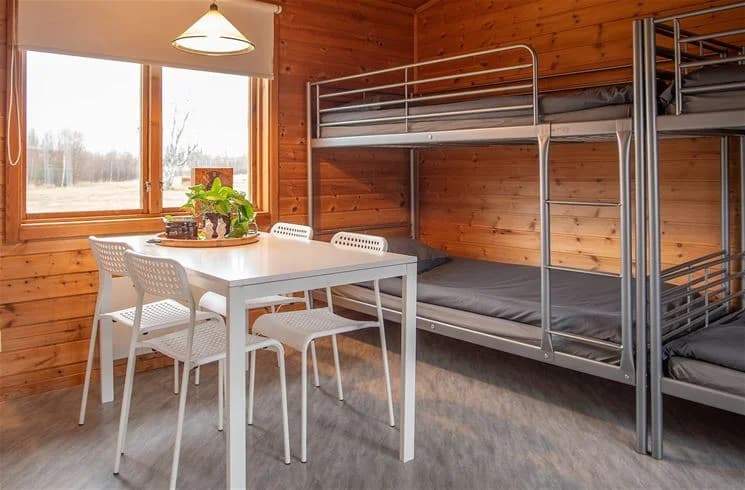 Bild av interiören i en rustik timmerstuga vid Nordmalings camping, med träväggar och golv av brunt trä som ger en mysig och naturlig atmosfär.