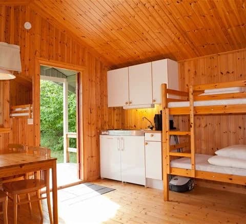 En interiörbild av en trästuga med träpaneler, dörrar och tak i mörk träfinish, typiskt för en rustik log cabin.
