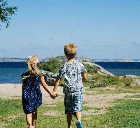 En somrig strand med glada barn som leker vid havet nära Marstrands Familjecamping.
