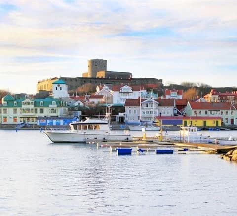 En avkopplande utsikt över en vattenväg med båtar, omgiven av kustlandskap vid Marstrands Familjecamping.