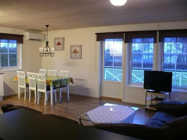 En interiörbild av Mjölknabbens camping med träinredning, golv och tak i trä, samt möbler. Rummet har ett enkelt och ljust designat interiör med ljusarmaturer.