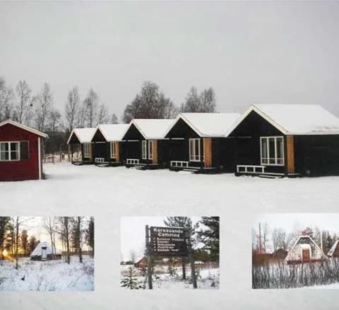 En snötäckt stuga ligger inbäddad i ett vintrigt landskap, omgiven av träbyggnader och isiga ytor, vid Karesuando camping & rekreation.