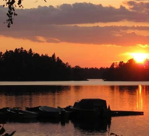 En vacker solnedgång vid Jälluntofta camping med spegelblanka vattenytor och en klar himmel, som skapar en lugn atmosfär i det natursköna landskapet.