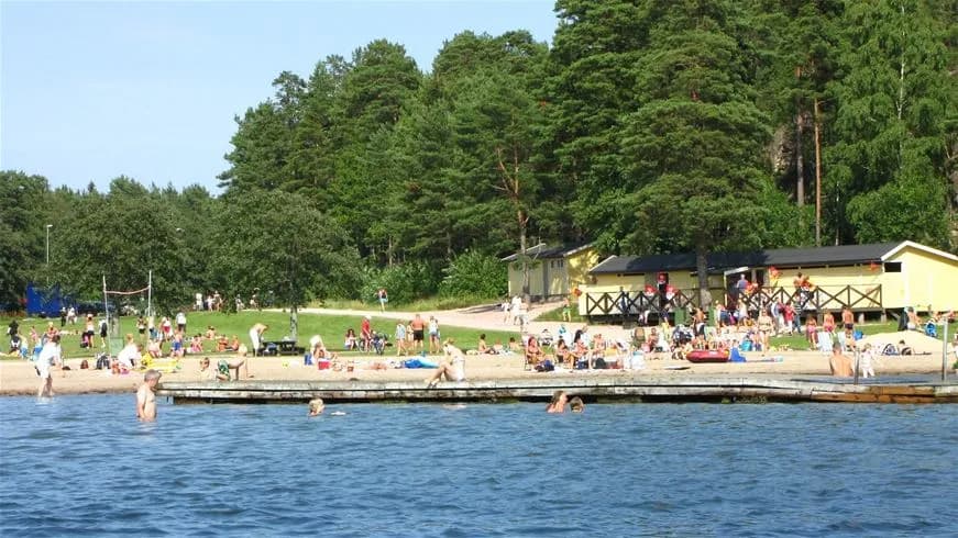 Bild av Jogersö Eco Camping visar en strand vid en kustlinje. Besökare njuter av fritidsaktiviteter och semester vid sjön, omgivna av vacker natur och avkopplande miljö.