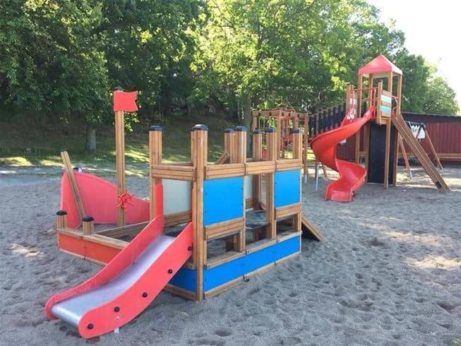 En bild av lekutrustning på Jogersö Eco Camping med en rutschkana i en öppen parkmiljö. Platsen erbjuder avkoppling och lek i en naturnära miljö.