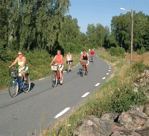 En cykel står parkerad på Ivö Camping, omgiven av grönska. Cykelns hjul och ram är framträdande i bilden.