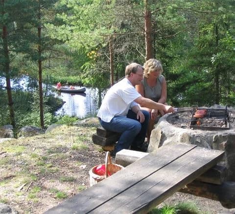 En picnicbord i ett skogsområde vid Hätteboda vildmarkscamping med utomhusmöbler för rekreation och en eldplats för besökare att njuta av naturen.