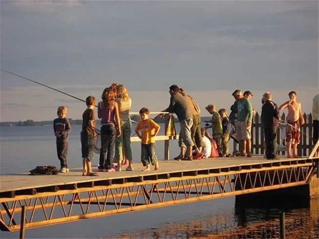 En träbrygga vid en lugn sjö omgiven av grönska på Hedesunda Camping, idealisk för rekreation och avkoppling.