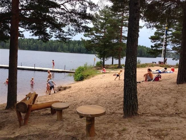 En campingplats vid Sävsjön i Grums, med utomhusmöbler placerade vid strandkanten, perfekt för avkoppling och semesteraktiviteter.
