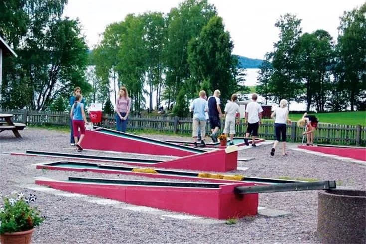 En grönskande camping med lekplats i förgrunden där barn leker.