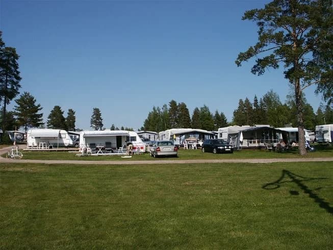 En grön campingplats med gräsmarker och träd, som erbjuder en naturnära upplevelse.