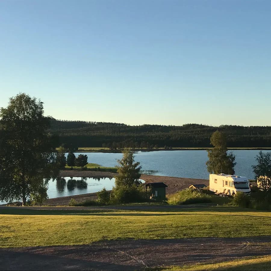 En lugn kvällsvy över en sjö vid Särna Camping, omgiven av öppna slätter och frodig natur.